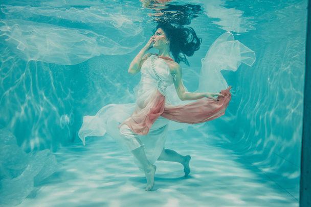 kaunis malli tyttö uinti vedenalainen naisellinen pitkä valkoinen ja vaaleanpunainen mekko
 - Valokuva, kuva