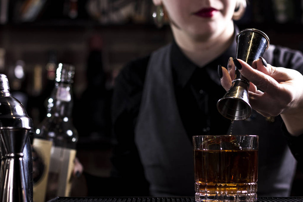 Cantinero haciendo cóctel refrescante sobre un fondo de bar. Estilo oscuro y malhumorado. Hielo en el vidrio
 - Foto, imagen