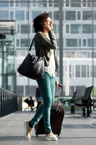 Całego ciała po stronie portret kobiety szczęśliwy podróży spaceru stacji z walizki i rozmowy na telefon  - Zdjęcie, obraz