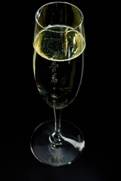glass with white sparkling wine champagne against a dark background - 写真・画像