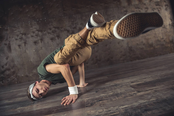 Young man break dancing on the wall background, performing tricks - Foto, imagen