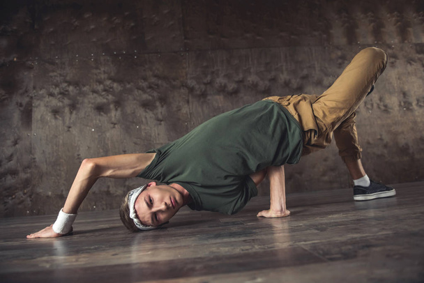 Young man break dancing on the wall background, performing tricks - Fotografie, Obrázek