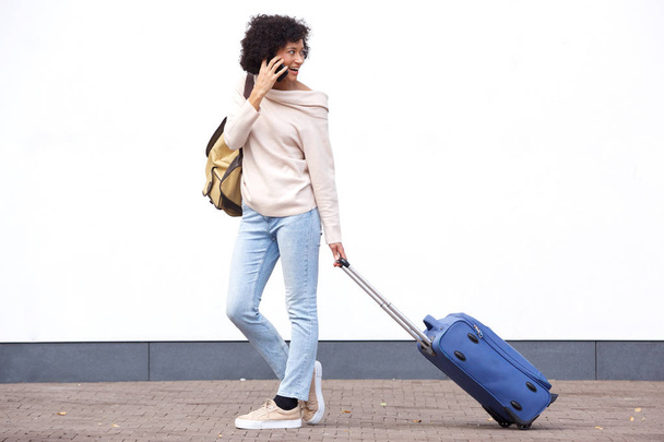 Täyspitkä muotokuva onnellinen matka nainen kävely matkalaukku ja puhuu matkapuhelimella
 - Valokuva, kuva