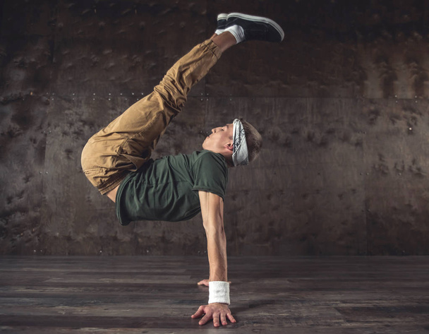Young man break dancing on the wall background, performing tricks - Fotó, kép