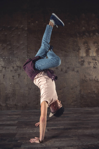 Молодий чоловік розбиває танці на фоні стіни, виконуючи трюки
 - Фото, зображення