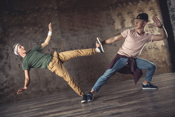 Fiatal férfiak break tánc a fal a háttérben, teljesítő trükkök - Fotó, kép