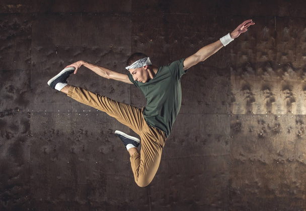junger Mann Breakdance auf der Wand Hintergrund, Kunststücke ausführen - Foto, Bild