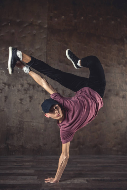 Young man break dancing on the wall background, performing tricks - Φωτογραφία, εικόνα