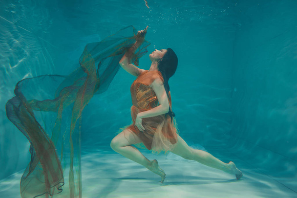 hermosa modelo chica nada bajo el agua en vestido naranja y disfruta de la relajación y la falta de estrés
 - Foto, imagen