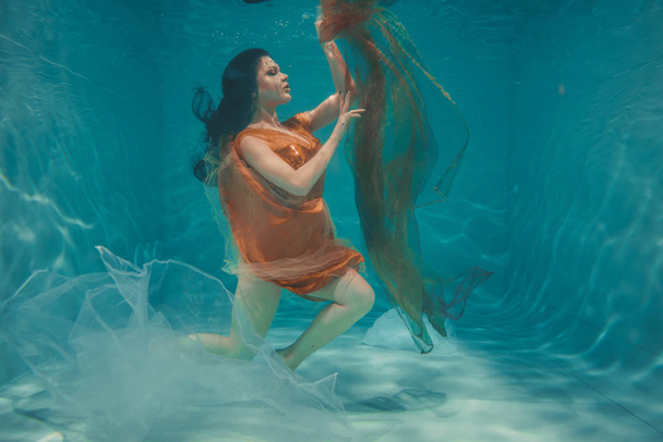 bella ragazza modello nuota sott'acqua in abito arancione e gode di relax e la mancanza di stress
 - Foto, immagini