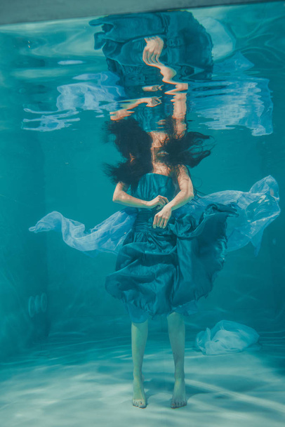 bela modelo menina nada debaixo d 'água em vestido azul e gosta de relaxamento e falta de estresse
 - Foto, Imagem