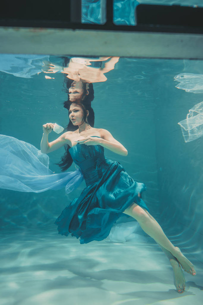 fille drôle s'amuser et boire du thé apaisant pour le petit déjeuner tout en nageant méditativement sous l'eau dans une robe
 - Photo, image