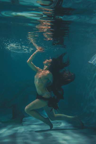 belle fille dans une combinaison transparente avec strass sur tout le corps nage sous l'eau comme un plongeur libre
 - Photo, image