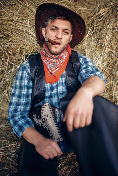 Vahşi kovboy puro ve tabanca, samanlık arka planda, Batı ile poz veriyor. Çiftlikte, vahşi batı kültür silahla Vintage erkek kişi - Fotoğraf, Görsel