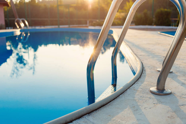 Egy része a medence egy rozsdamentes acél létra és kék a sunset részlete. Nyaralás, üdülés, relax, nyári tevékenységek koncepció - Fotó, kép