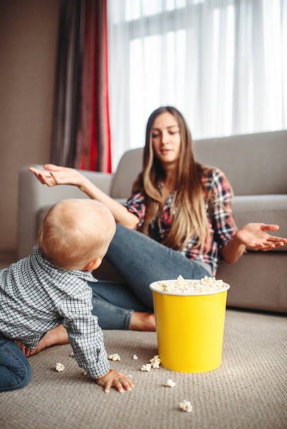 Małe dziecko popcorn rozlane na podłodze, macierzyństwo problemy. Smutna Mama i syn razem w domu, rodzicielstwa - Zdjęcie, obraz