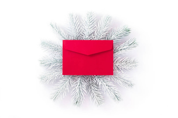Conceptual photo. White hand painted spruce branches frame a bright red envelope symbolizing the message. - Photo, image