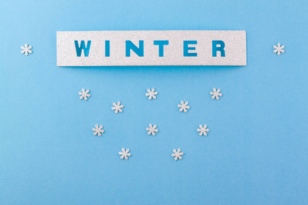 Confetti and handmade lettering scrabbooking in the form of an inscription WINTER and small snowflakes. Conceptual photo. - Фото, изображение