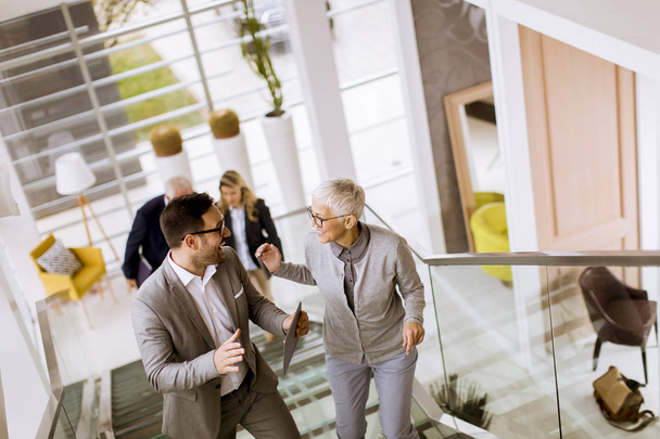 Группа бизнесменов и бизнесвумен, идущих и поднимающихся по лестнице в офисном здании
 - Фото, изображение