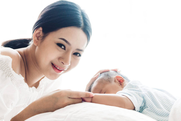 Mother holding baby hand on white bed.Love of family concept - 写真・画像
