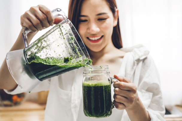 Zdravá žena se těší, aby zelená zelenina detox čistit a zelené ovoce smoothie s mixérem v kuchyni doma. - Fotografie, Obrázek