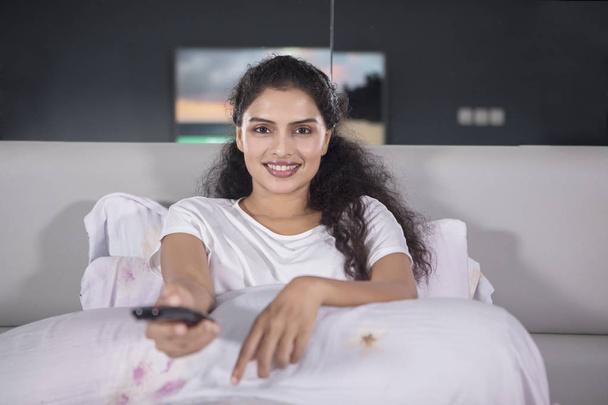 Egy boldog asszony ült az ágyon, otthon tévénézés közben képe - Fotó, kép