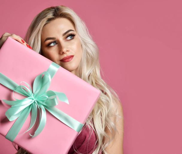 Beautiful woman hold pink and pastel green Christmas presents gift box for new year celebration smiling on pink  - Zdjęcie, obraz
