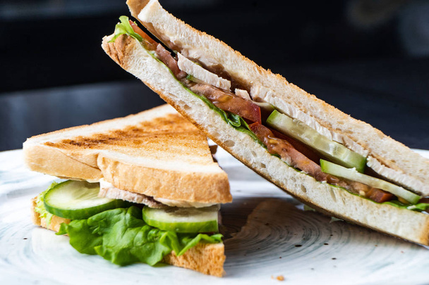 Сэндвич с ветчиной, сыром, помидорами, салатом и жареным хлебом. Вид сверху изолирован на темном фоне
 - Фото, изображение