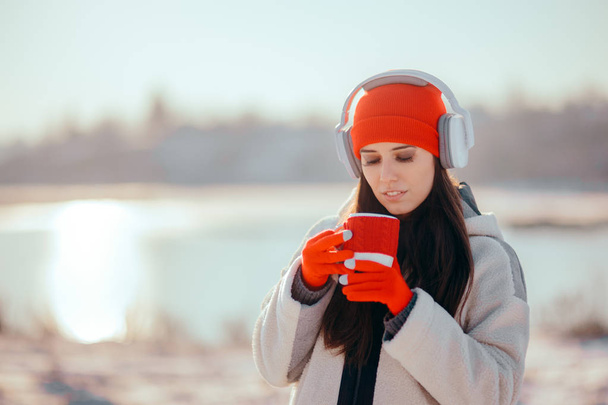Зимова жінка п'є гарячий напій слухаючи музику
 - Фото, зображення