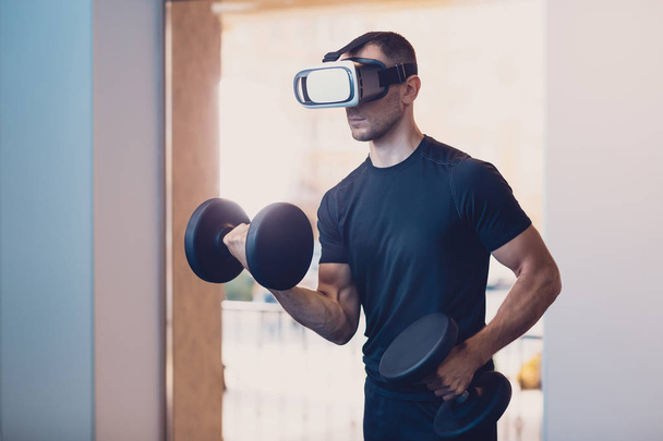 Man wearing virtual reality glasses with dumbbells - Фото, зображення