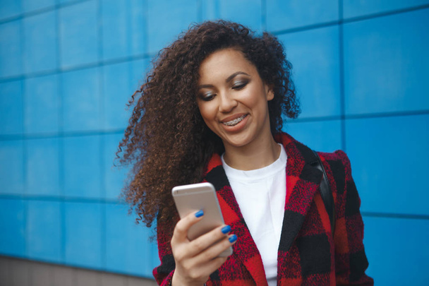 Красивая улыбающаяся женщина с мобильным телефоном ходит по улице
 - Фото, изображение