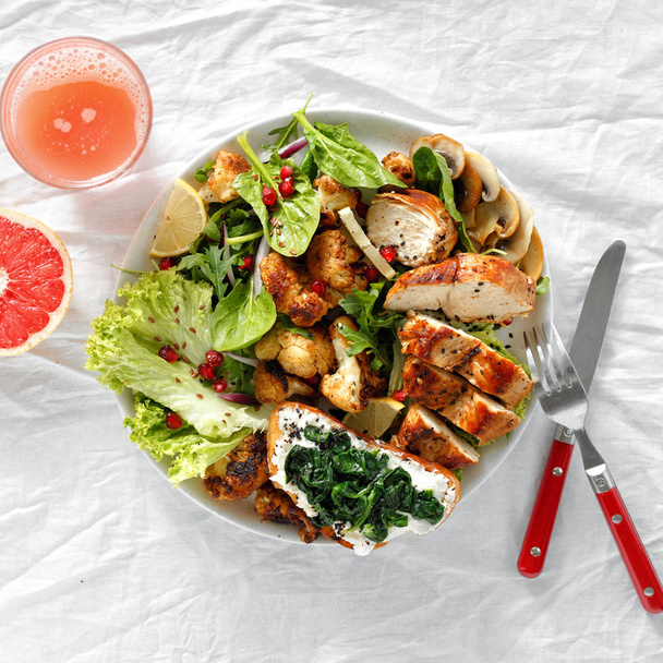 Healthy food concept. Lunch food bowl of fresh salad with hicken steak and fried cauliflower on white background with grapefruit fresh top view - Fotó, kép