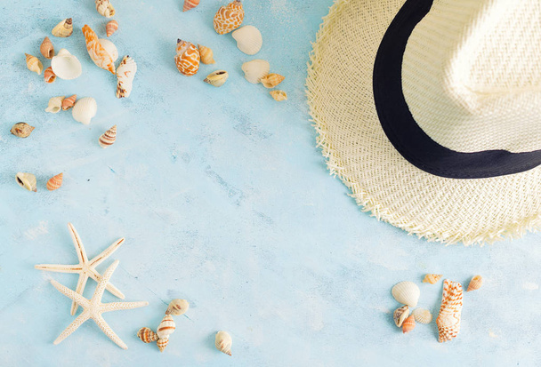 Καλοκαιρινές διακοπές κοροϊδεύω: ψάθινο καπέλο, κοχύλια και αστερίες λευκό σε μπλε φόντο. Ταξίδια, concept παραλίας. Χώρο για κείμενο ή γράμματα - Φωτογραφία, εικόνα