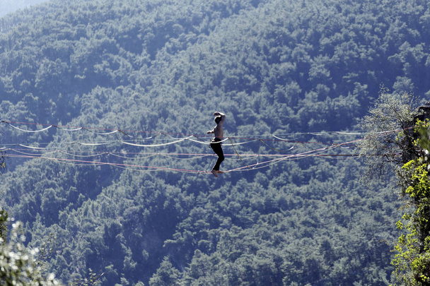 Magasvonalas egy kötélen. Highline a háttérben a hegyek. Extrém sport a természetben. Kiegyensúlyozom a parittyát. Egyensúly magasságban. - Fotó, kép
