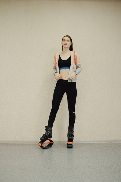 young girl exercising with kangoo shoes. beautiful and sport girl in the gym training. Kangoo jumping. Beautiful girls in Kangoo Jumping training in the gym - Φωτογραφία, εικόνα