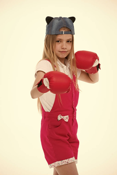 Child in boxing gloves isolated on white. Little girl before training or workout. Kid athlete in fashionable cap. Fashion, style and trend. Sport activity and energy - Photo, Image