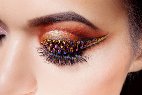 Amazing Bright eye makeup with a arrow with rhinestones. Brown and gold tones, colored eyeshadow - Foto, Imagem
