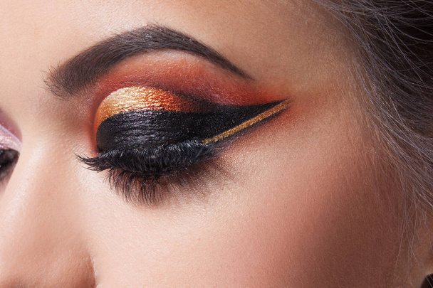 Amazing Bright eye makeup with a wide arrow. Brown and gold tones, colored eyeshadow - 写真・画像