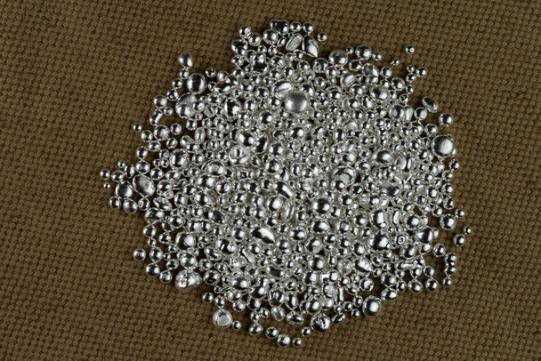 Купка срібних зерен на тлі грубої текстури текстилю
. - Фото, зображення