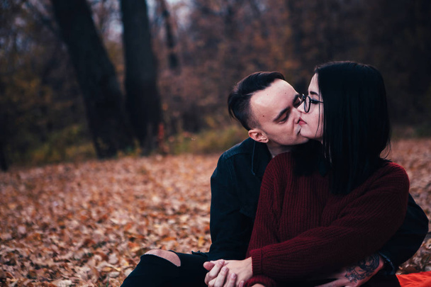 młody mężczyzna i kobieta młody siedzi na kratę w lesie jesienią. - Zdjęcie, obraz