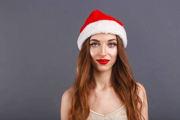 Beautiful Girl In A Santa Hat Staying On A Gray Background - Photo, Image