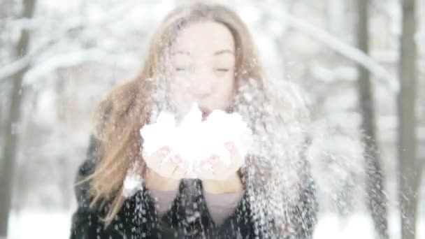 Een jonge vrouw houdt van sneeuw in haar handen. - Video