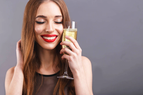 ehrfürchtige langhaarige Frau trinkt ein Glas Champagner - Foto, Bild