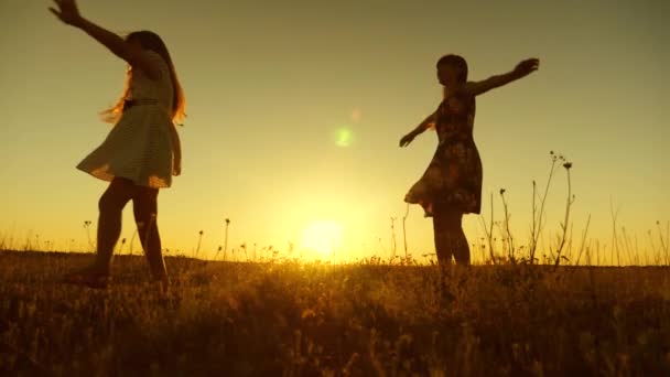 meninas felizes dançando em raios de belo pôr do sol no parque. Adolescentes com cabelos longos rodopiam em voo sob raios de sol dourado. Movimento lento
. - Filmagem, Vídeo