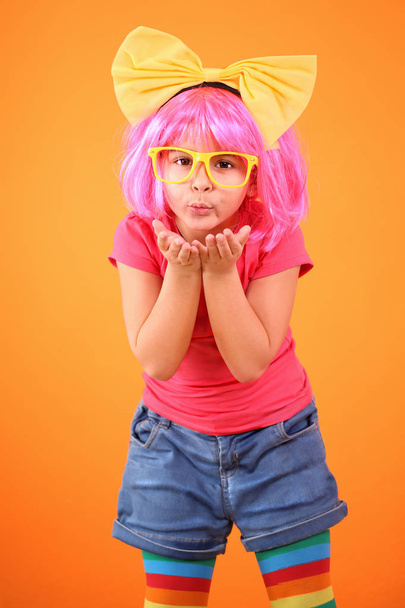 Beautiful five years girl with a pink wig throwing a kiss on an orange background - Fotografie, Obrázek