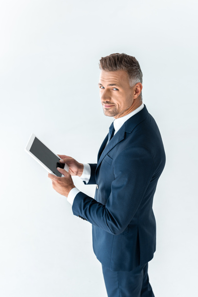 high angle view of handsome businessman holding tablet with blank screen and looking at camera isolated on white - Photo, Image