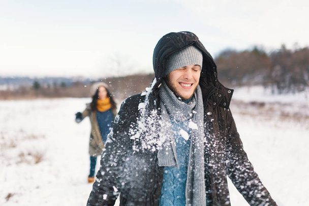 Sneeuwballengevecht. Winter paar plezier spelen in sneeuw buiten. Jonge vrolijke tevreden jonge man en vrouw. - Foto, afbeelding