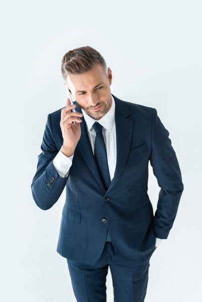 Hochwinkelaufnahme eines gutaussehenden Geschäftsmannes im blauen Anzug, der per Smartphone isoliert auf Weiß spricht - Foto, Bild