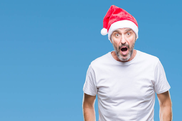中年恐れ、驚きの表情でショックを受けて孤立の背景にクリスマスの帽子を身に着けている白髪の年配の男性恐怖し、興奮の顔. - 写真・画像
