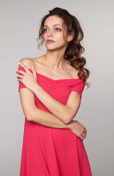 beautiful young woman in pink dress looking away. Isolated on studio grey background - Foto, Bild